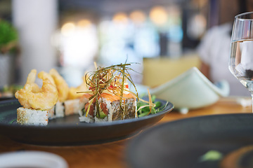 Image showing Sushi restaurant, catering and seafood in closeup for service, brunch or dinner with wine, glass and fish meal. Japanese cuisine, menu and table in diner, cafe or luxury for health, nutrition or diet