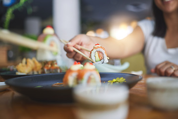 Image showing Chopstick, hand and eating sushi food at restaurant for nutrition at table. Closeup of hungry people with wooden sticks for dining, Japanese culture and cuisine while sharing with creativity on plate