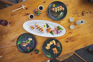 Image showing Sushi, seafood and chopsticks in an asian restaurant from above for fine dining or traditional cuisine. Salmon, menu and chinese food with a dish on a table in a local eatery for hunger or nutrition