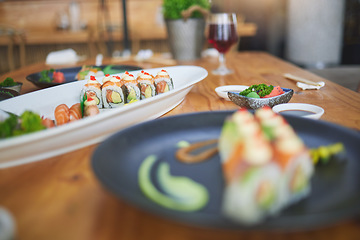 Image showing Sushi, chinese food and chopsticks in an asian restaurant closeup for fine dining or traditional cuisine. Salmon, menu and seafood with a dish on a table in a local eatery for hunger or nutrition