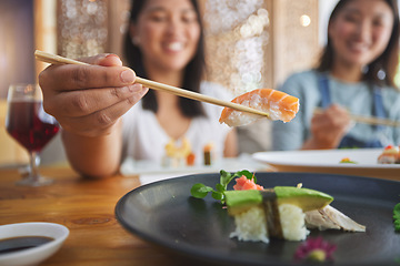 Image showing Japanese woman, chopsticks and nigiri in restaurant, smile and excited for fine dining at party. Asian friends, fish and healthy with culture, traditional and fast food in diner, sushi bar or store