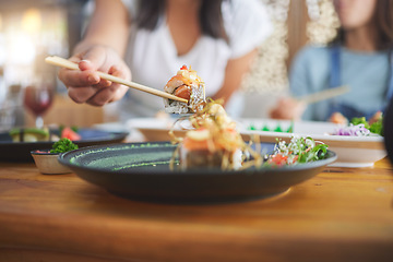 Image showing Sushi, hand and eating food with chopsticks at a restaurant for nutrition and health. Closeup of a hungry people with wooden sticks for dining, Japanese culture and cuisine with creativity on plate