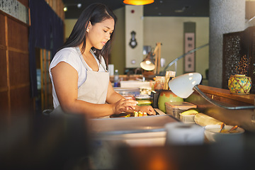 Image showing Chinese food, cooking and an asian woman in a sushi restaurant to serve a traditional meal for nutrition. Kitchen, recipe and preparation with a young chef in an eatery for fine dining cuisine