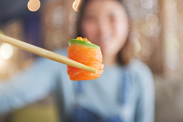 Image showing Food, eating sushi and person with chopsticks at restaurant for nutrition and health. Closeup of a woman with wooden sticks for dining, Japanese culture and salmon cuisine with creativity on fish