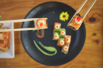 Image showing Sushi, seafood and chopsticks in a chinese restaurant from above for dining or traditional cuisine. Salmon, menu and raw food with am asian dish on a table in a local eatery for hunger or nutrition