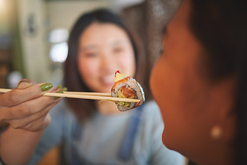 Image showing Chopsticks, restaurant feeding and friends hands with sushi and Asian cuisine eating at cafe. Happy, hungry women and plate of food at Japanese bar with friendship, smile and bonding from table meal