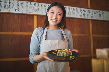 Image showing Restaurant, portrait and female waitress with sushi for serving a food order with a smile. Happy, lunch and young Asian server with a plate of a Japanese recipe or meal at a traditional cuisine cafe.