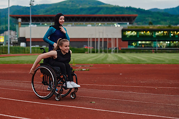 Image showing A Muslim woman in a burqa running together with a woman in a wheelchair on the marathon course, preparing for future competitions.