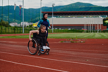 Image showing A Muslim woman in a burqa running together with a woman in a wheelchair on the marathon course, preparing for future competitions.