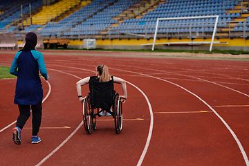 Image showing A Muslim woman in a burqa running together with a woman in a wheelchair on the marathon course, preparing for future competitions.