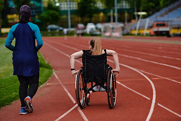 Image showing A Muslim woman in a burqa running together with a woman in a wheelchair on the marathon course, preparing for future competitions.