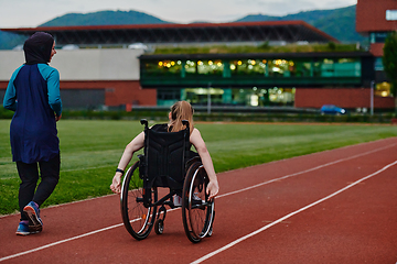 Image showing A Muslim woman in a burqa running together with a woman in a wheelchair on the marathon course, preparing for future competitions.