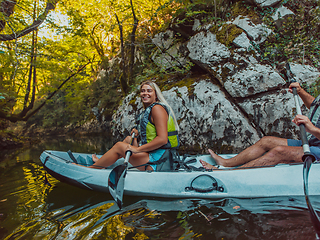 Image showing A young couple enjoying an idyllic kayak ride in the middle of a beautiful river surrounded by forest greenery