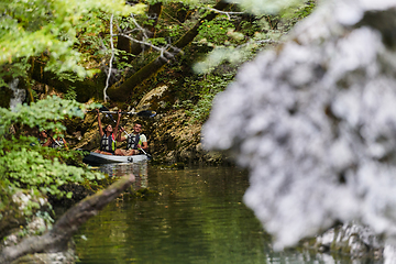 Image showing A young couple enjoying an idyllic kayak ride in the middle of a beautiful river surrounded by forest greenery