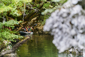 Image showing A young couple enjoying an idyllic kayak ride in the middle of a beautiful river surrounded by forest greenery