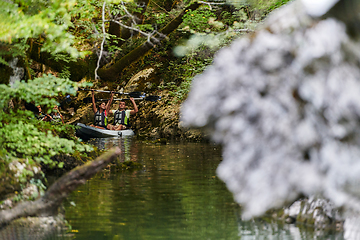 Image showing A young couple enjoying an idyllic kayak ride in the middle of a beautiful river surrounded by forest greenery