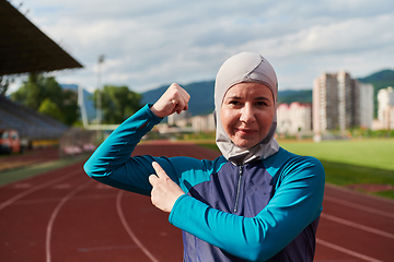 Image showing A hijab woman in a burqa showing her boldness by showing her muscles on her arms