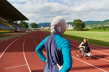 Image showing A Muslim woman wearing a burqa resting with a woman with disability after a hard training session on the marathon course