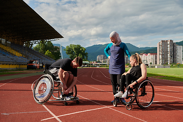 Image showing A woman with a disability in a wheelchair talking after training with a woman wearing a hijab and a man in a wheelchair