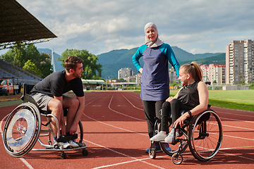 Image showing A woman with a disability in a wheelchair talking after training with a woman wearing a hijab and a man in a wheelchair