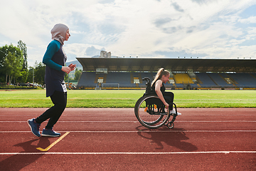 Image showing A Muslim woman in a burqa running together with a woman in a wheelchair on the marathon course, preparing for future competitions.