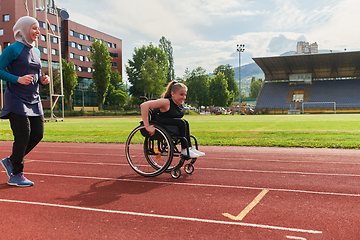 Image showing A Muslim woman in a burqa running together with a woman in a wheelchair on the marathon course, preparing for future competitions.