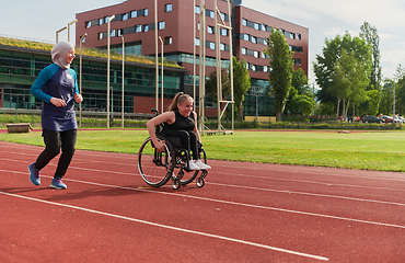 Image showing A Muslim woman in a burqa running together with a woman in a wheelchair on the marathon course, preparing for future competitions.