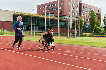 Image showing A Muslim woman in a burqa running together with a woman in a wheelchair on the marathon course, preparing for future competitions.