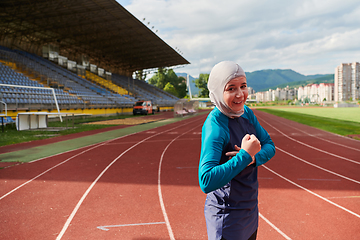 Image showing A hijab woman in a burqa showing her boldness by showing her muscles on her arms