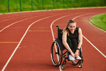 Image showing A smiling woman with disablitiy sitting in a wheelchair and resting on the marathon track after training