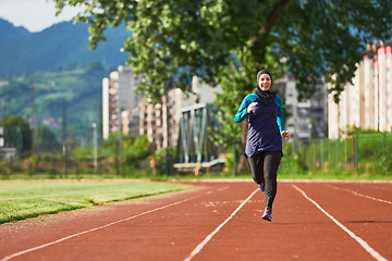 Image showing A muslim woman in a burqa sports muslim clothes running on a marathon course and preparing for upcoming competitions