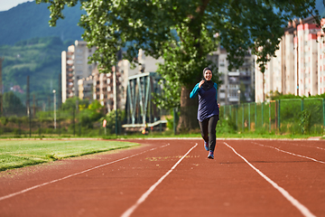 Image showing A muslim woman in a burqa sports muslim clothes running on a marathon course and preparing for upcoming competitions