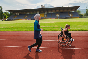 Image showing A Muslim woman in a burqa running together with a woman in a wheelchair on the marathon course, preparing for future competitions.