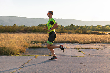 Image showing Triathlete in professional gear running early in the morning, preparing for a marathon, dedication to sport and readiness to take on the challenges of a marathon.