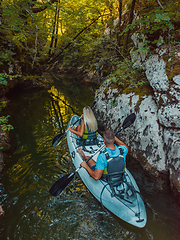 Image showing A young couple enjoying an idyllic kayak ride in the middle of a beautiful river surrounded by forest greenery