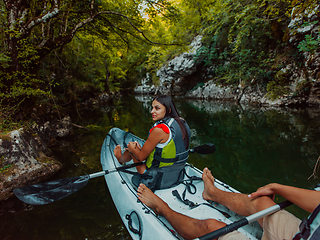 Image showing A young couple enjoying an idyllic kayak ride in the middle of a beautiful river surrounded by forest greenery