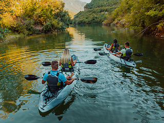 Image showing A group of friends enjoying having fun and kayaking while exploring the calm river, surrounding forest and large natural river canyons