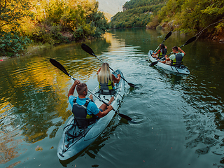 Image showing A group of friends enjoying having fun and kayaking while exploring the calm river, surrounding forest and large natural river canyons