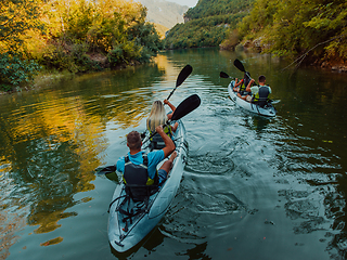 Image showing A group of friends enjoying having fun and kayaking while exploring the calm river, surrounding forest and large natural river canyons