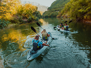 Image showing A group of friends enjoying having fun and kayaking while exploring the calm river, surrounding forest and large natural river canyons