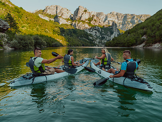 Image showing A group of friends enjoying having fun and kayaking while exploring the calm river, surrounding forest and large natural river canyons