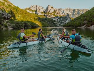 Image showing A group of friends enjoying having fun and kayaking while exploring the calm river, surrounding forest and large natural river canyons