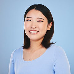 Image showing Happy, smile and portrait of Asian woman in a studio with a natural, makeup and beauty face. Self care, cosmetics and headshot of a young female model with a cosmetology routine by a blue background.