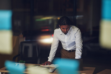 Image showing Business man, night and planning in office, documents and reading for proposal, goals or deadline for report. Entrepreneur, paperwork and glass for sticky note, thinking and ideas in dark workplace