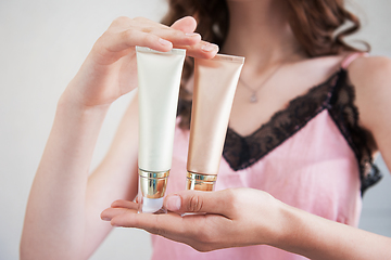 Image showing female hands holding cosmetic cream tubes.