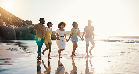 Image showing Happy, holding hands and sunset with friends at beach for freedom, support and travel. Wellness, energy and summer with group of people walking by the sea for peace, adventure and vacation together