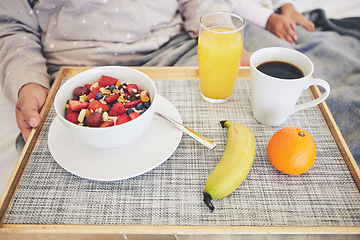 Image showing Tray, hands and closeup of healthy breakfast in bed in the room of modern house on a weekend. Morning, diet and zoom of cereal with fruit, orange juice and cup of coffee for mother and child at home.