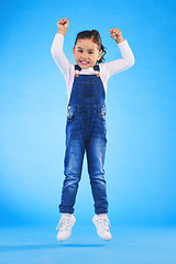 Image showing Jump, smile and portrait of a child in a studio with energy, achievement or good news with excitement. Happy, youth and full length of a girl kid model moving for winning by isolated blue background.