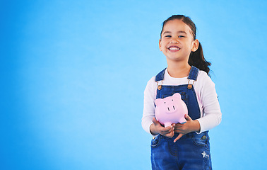 Image showing Girl child, piggy bank and studio portrait with mockup space, saving and financial education by blue background. Female kid, money box and happy with goal, investing and learning discipline with cash