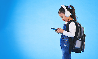 Image showing Music, backpack and child on blue background with phone ready for school, learning and education. Kindergarten, studio and young girl with bag on smartphone for streaming song, audio and radio